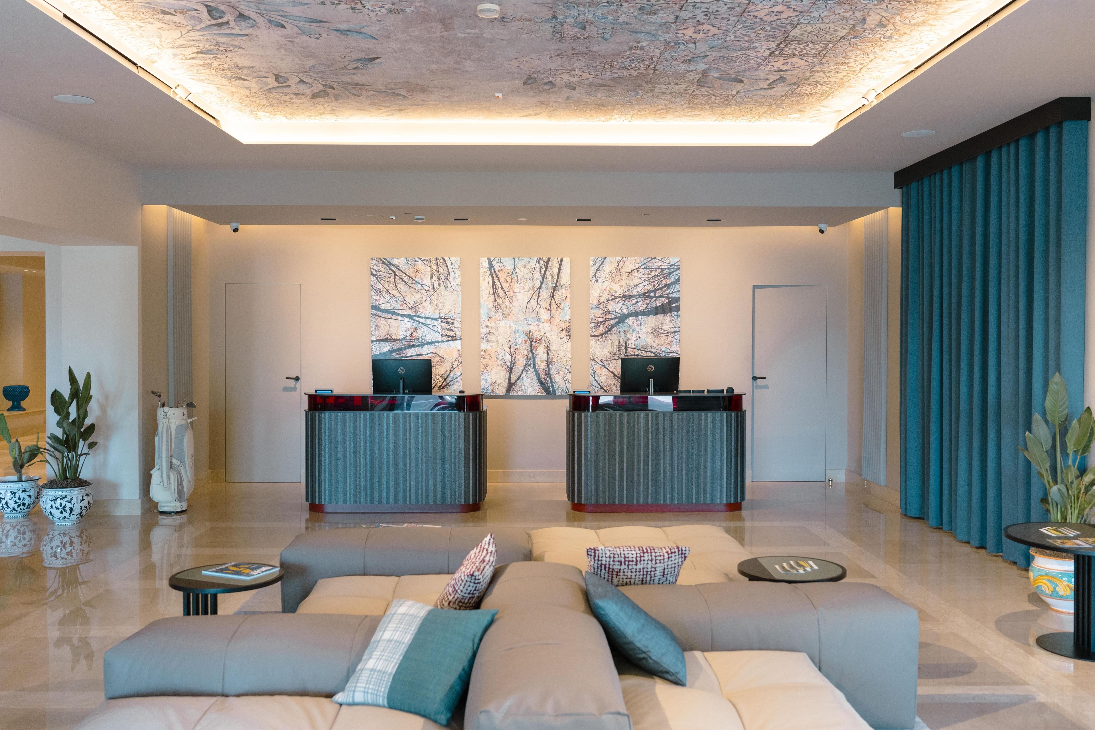 A modern lobby with a reception desk, seating area, and artwork on the walls.