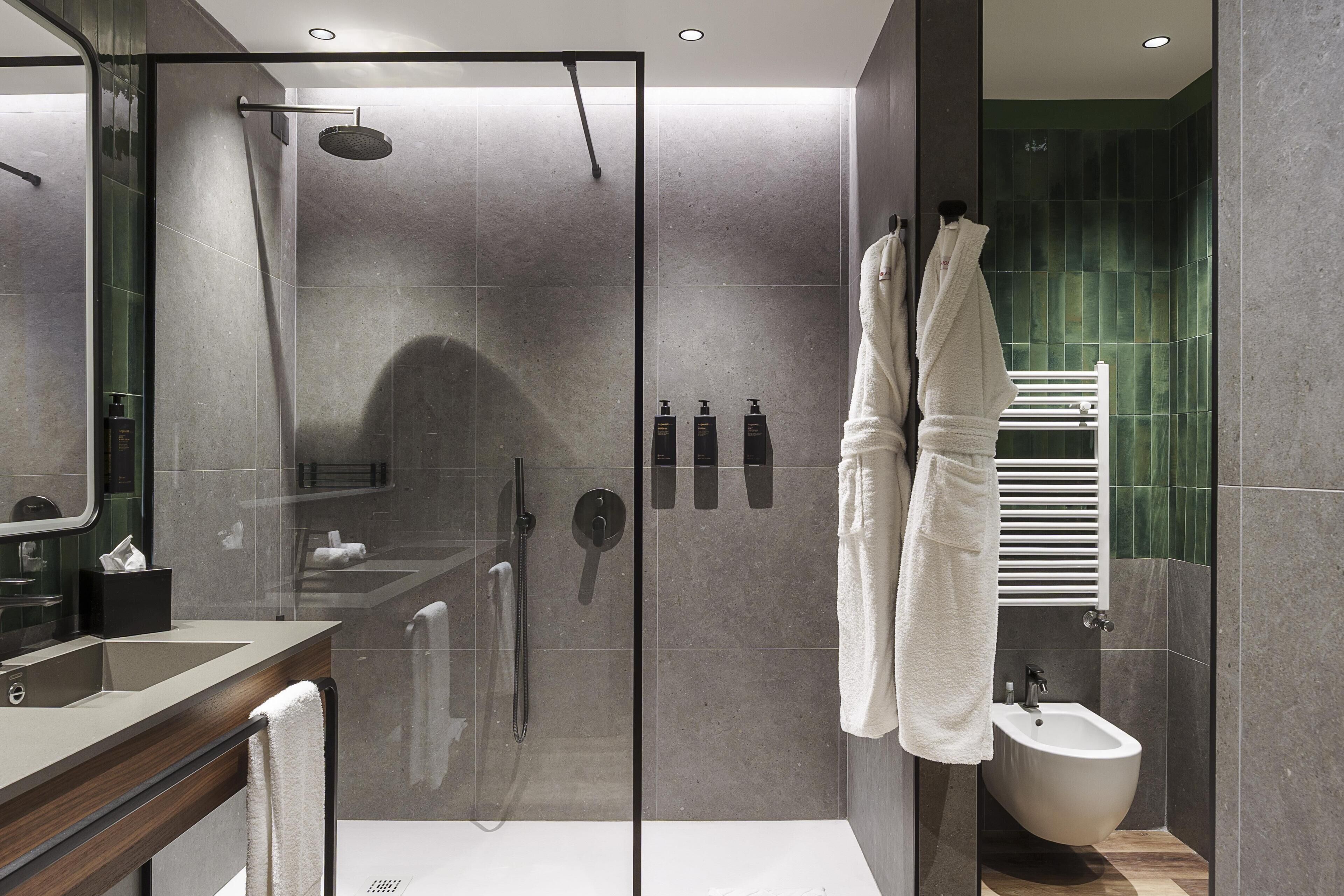 A modern bathroom with a glass-enclosed shower, a bidet, and a vanity with a mirror.