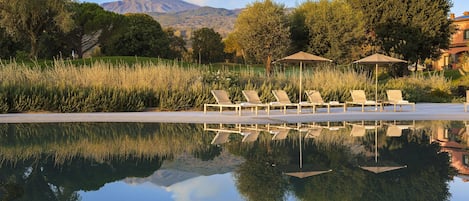 Una piscina al aire libre de temporada, sombrillas