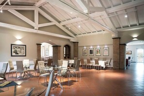 A spacious dining area with high ceilings and exposed beams, featuring multiple tables and chairs. - Picciolo Etna Golf Resort & Spa, Curio Collection by Hilton (Castiglione di Sicilia)
