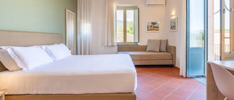 A hotel room with a bed, a sofa, a desk, and a window with a view.