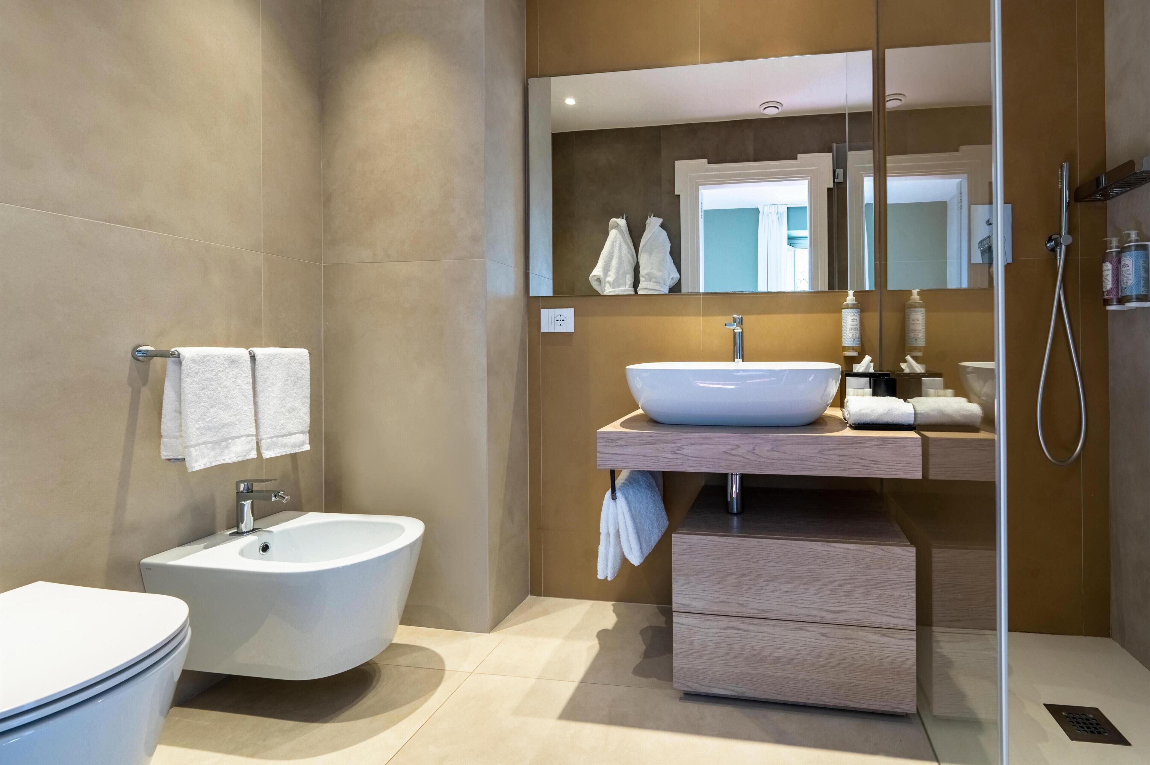 Un bagno moderno con bidet, lavabo e specchio.