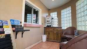 A small room with a window, a sink, a cabinet, a chair, and a trash bin. - Rodeway Inn Ventura Midtown (Ventura)