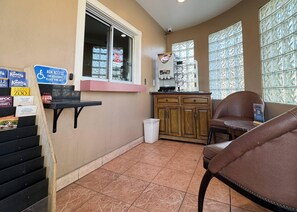 A small room with a window, a sink, a cabinet, a chair, and a trash bin. - Rodeway Inn Ventura Midtown (Ventura)