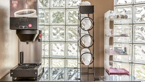 Eine Kaffeemaschine, ein Bechergestell und eine Vitrine mit Auslagen.
