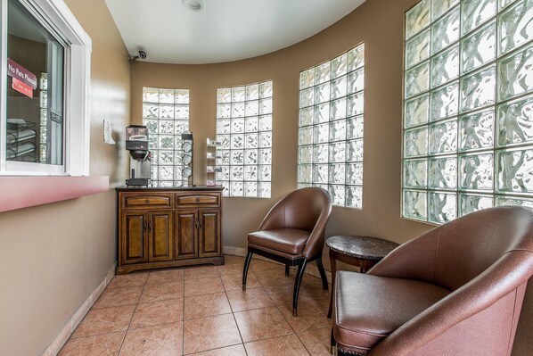 A room with a curved ceiling, a wooden cabinet, a coffee machine, two leather chairs, and large windows with a grid pattern. - Rodeway Inn Ventura Midtown (Ventura)