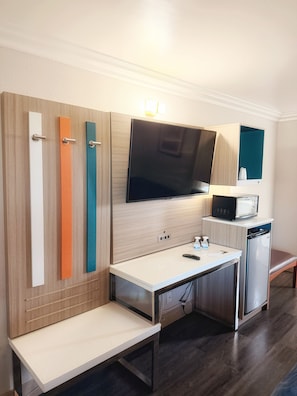 Una kitchenette compacta con microondas, un refrigerador pequeño, un lavamanos y un banco.