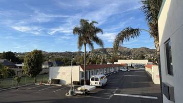 A parking lot with a white van, a white car, and a building with a red roof.