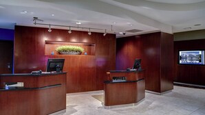 A reception area with two wooden reception desks, a potted plant, and a digital display.