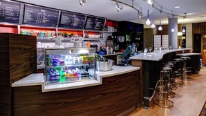 A modern bar area with a refrigerated display, bar stools, and a menu board above.