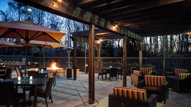 An outdoor patio area with tables and chairs, a fire feature, and umbrellas.