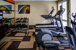 Un gimnasio con cintas de correr, mancuernas y un banco de pesas.