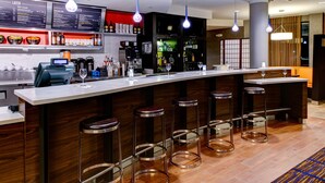 A bar area with a long counter, multiple stools, and a menu board above.