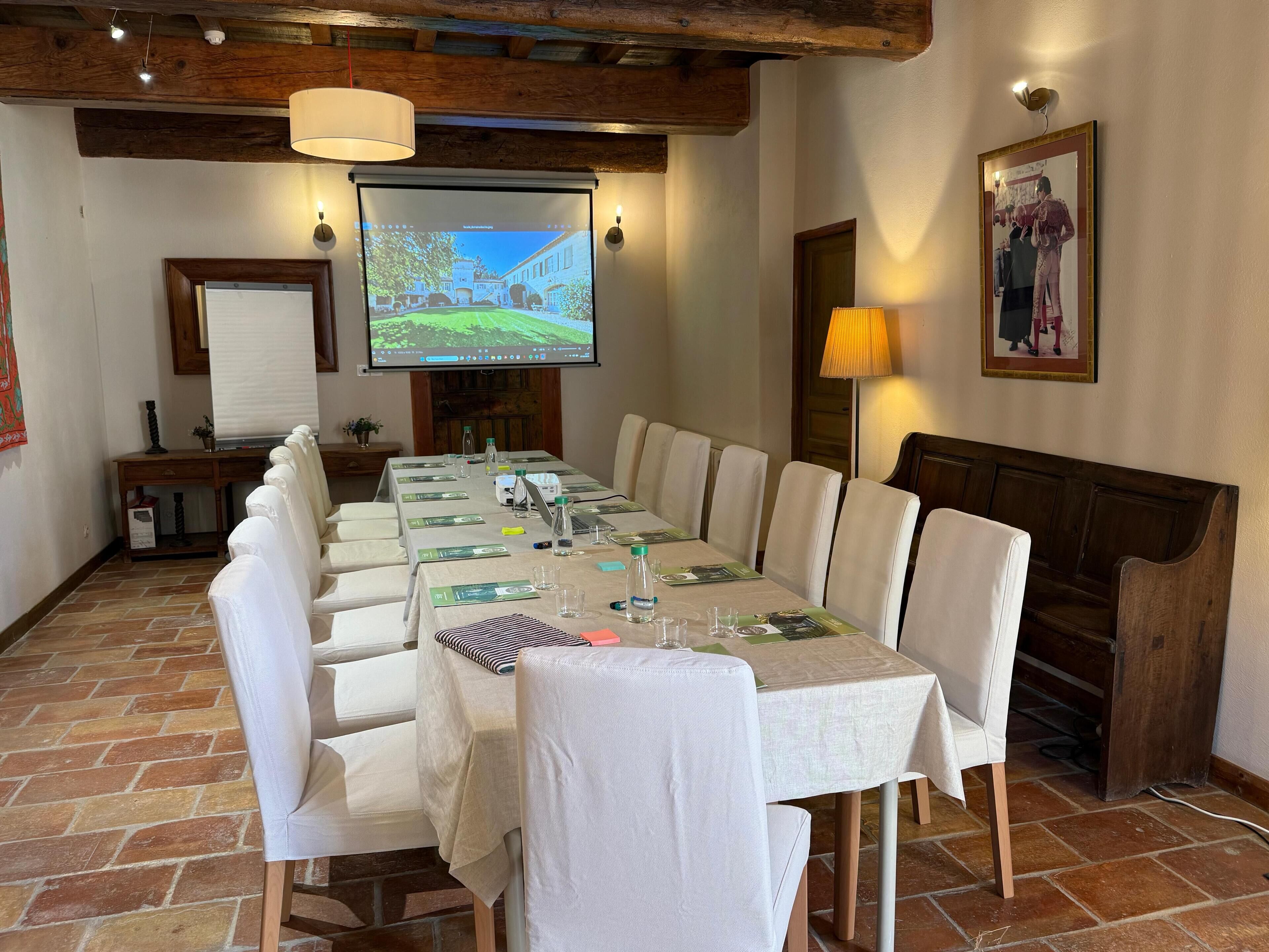 Una sala de conferencias con una larga mesa, sillas, una pantalla de proyector y una chimenea.