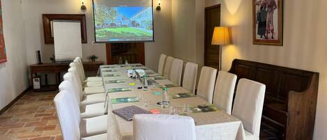 Una sala de conferencias con una larga mesa, sillas, una pantalla de proyector y una chimenea.