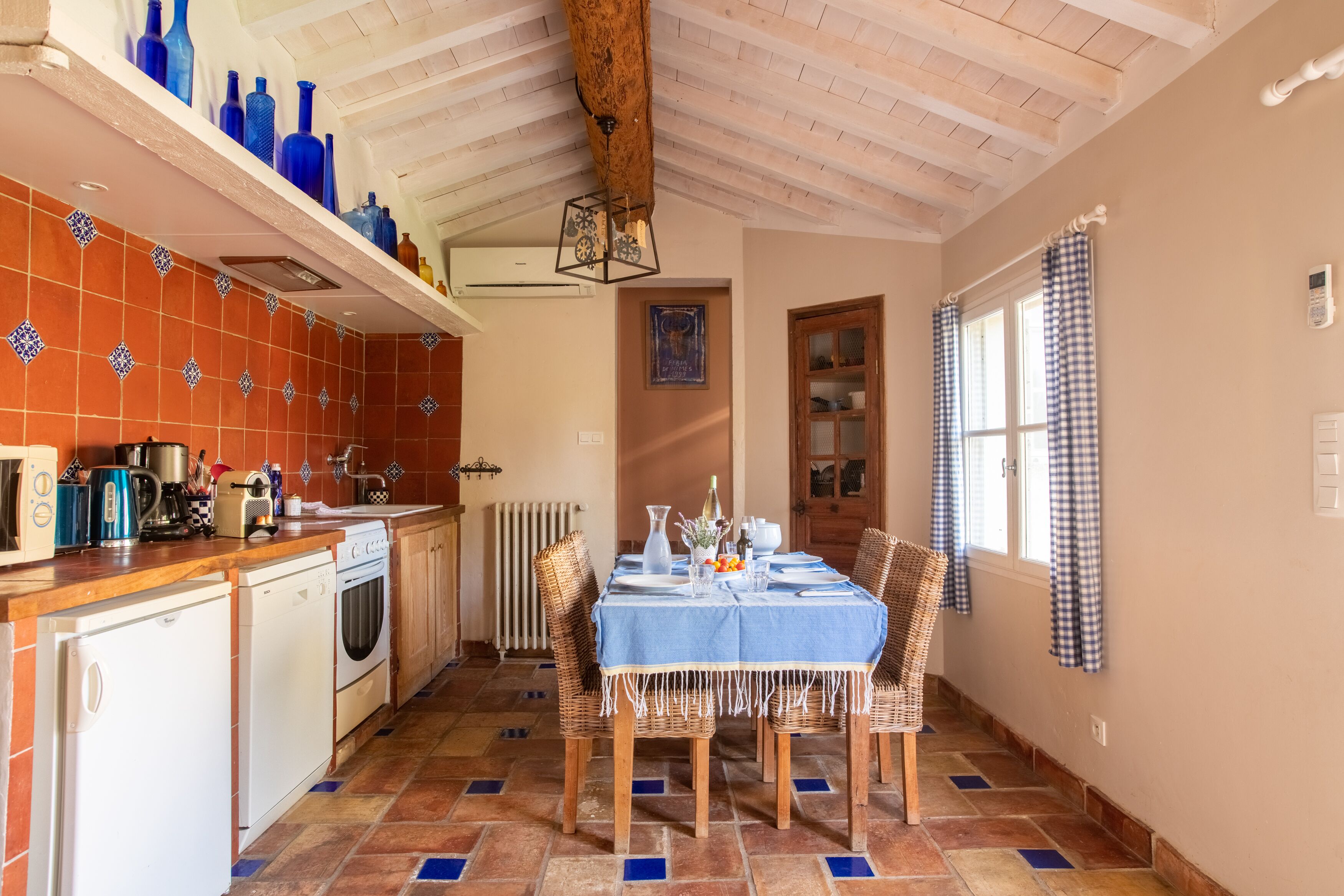 A kitchen with a dining table set for four, a built-in oven, and a tiled backsplash.