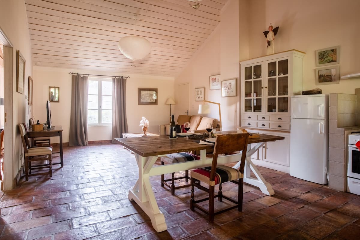 Una habitación acogedora con una mesa de madera, sillas, un sofá, un armario y un refrigerador.