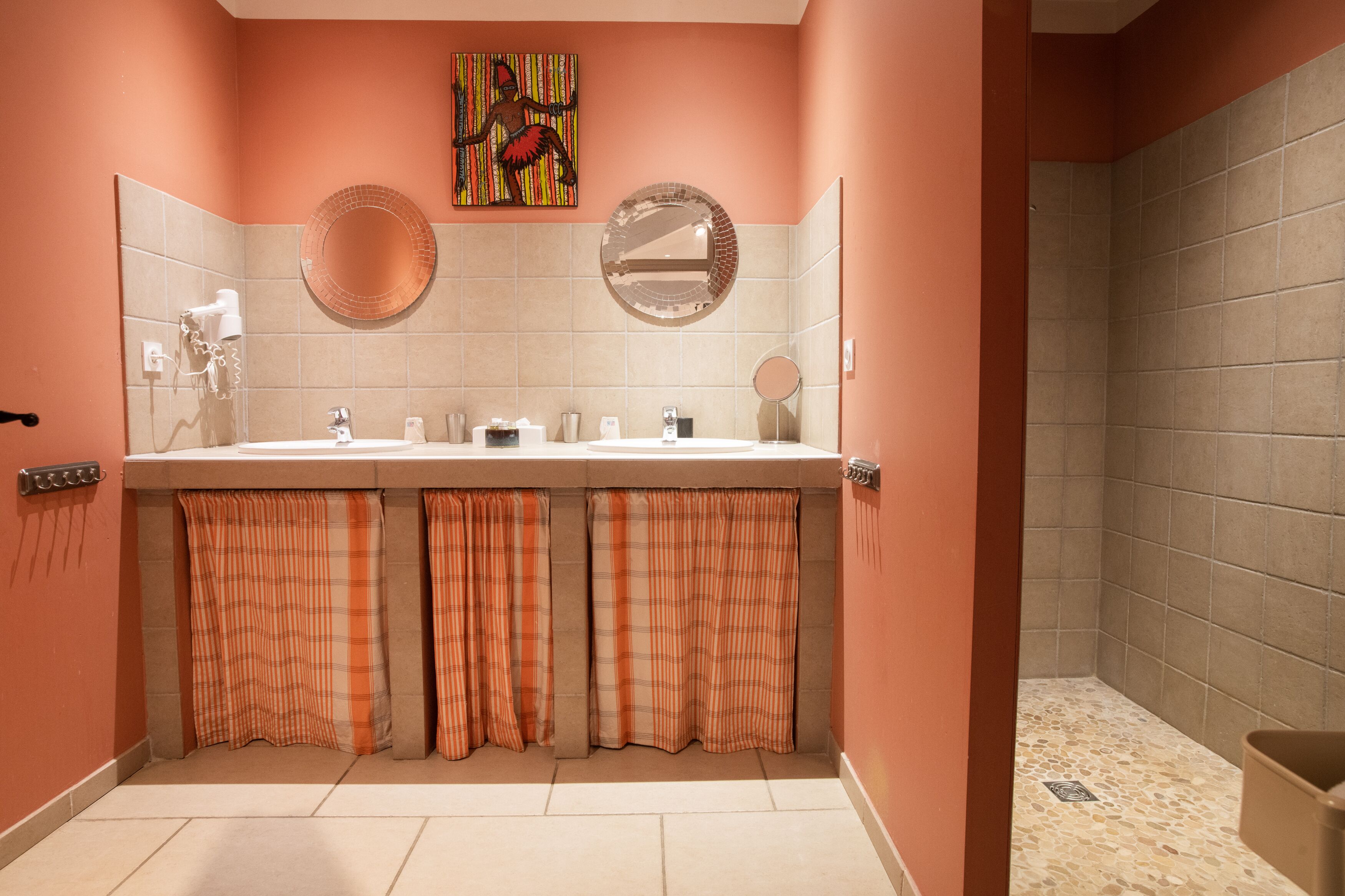 A bathroom with a double sink, a mirror, and a shower area.