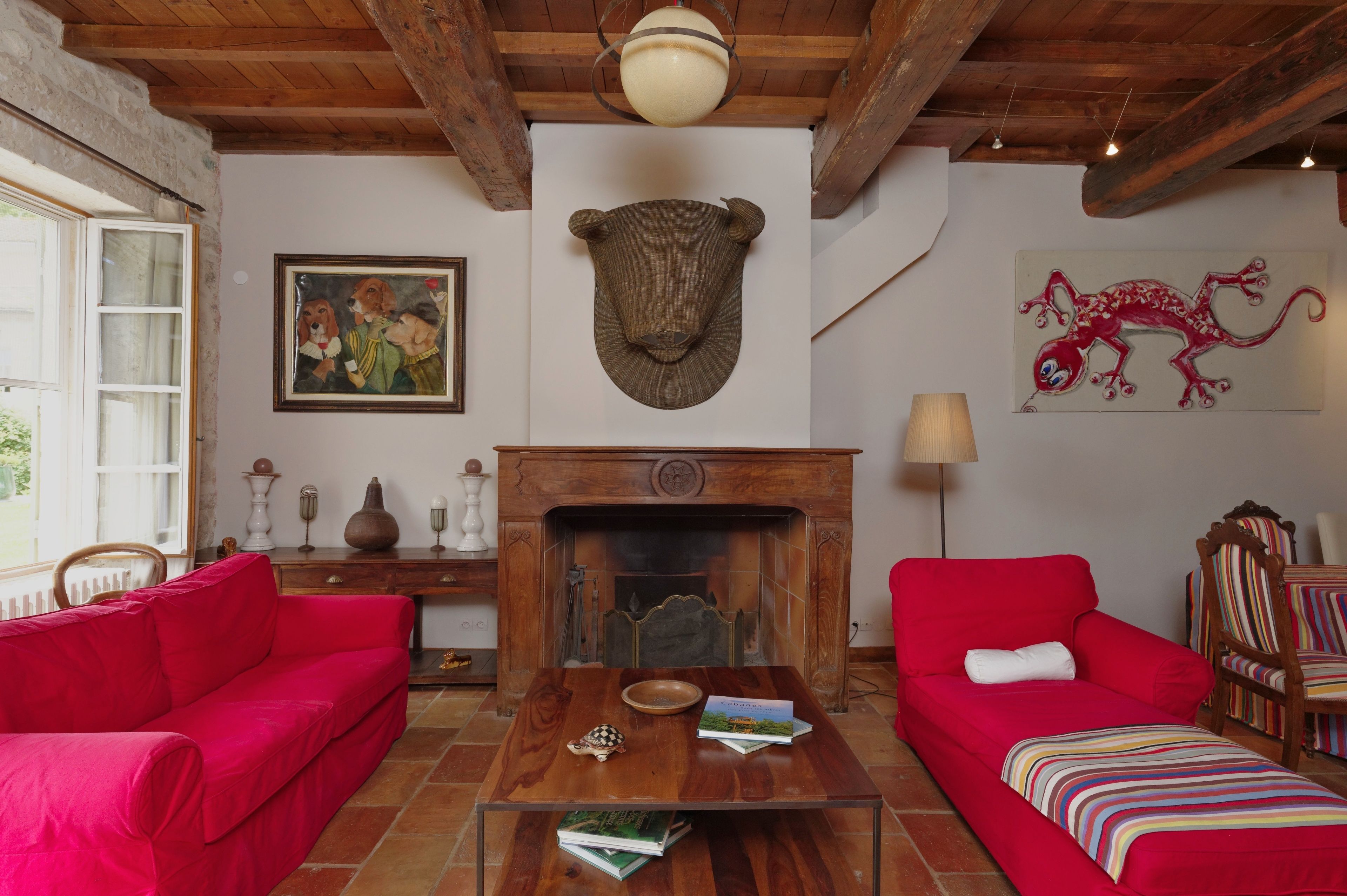 Une pièce chaleureuse avec deux canapés rouges, une table basse en bois, une cheminée et une bibliothèque.