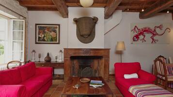 Une pièce chaleureuse avec deux canapés rouges, une table basse en bois, une cheminée et une bibliothèque.