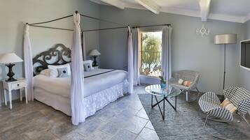 A bedroom with a four-poster bed, a glass coffee table, and two rocking chairs.
