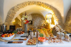Un buffet proposant une variété de plats, avec une arche en pierre en arrière-plan.