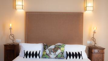 A neatly made bed with white and black pillows, two bedside tables with lamps, and a plain wall.