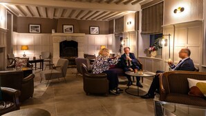 A cozy lounge area with leather sofas, a fireplace, and framed pictures on the walls. - Hostellerie Du Royal Lieu (Compiègne)