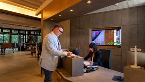A reception desk in a modern building with a large window, a piano, and a sign with "R" on it. - Hostellerie Du Royal Lieu (Compiègne)