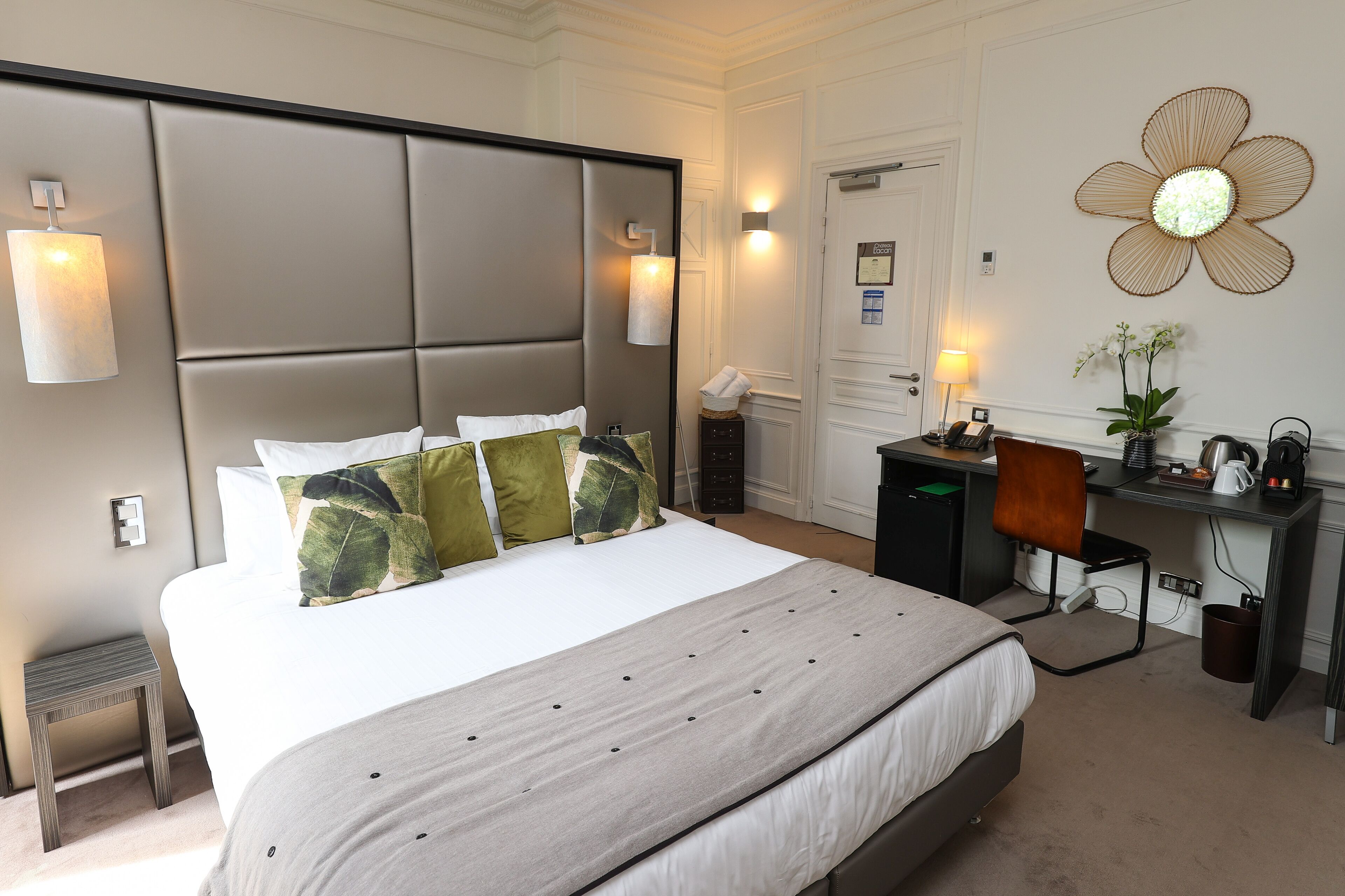 A hotel room with a large bed, a desk, and a chair.