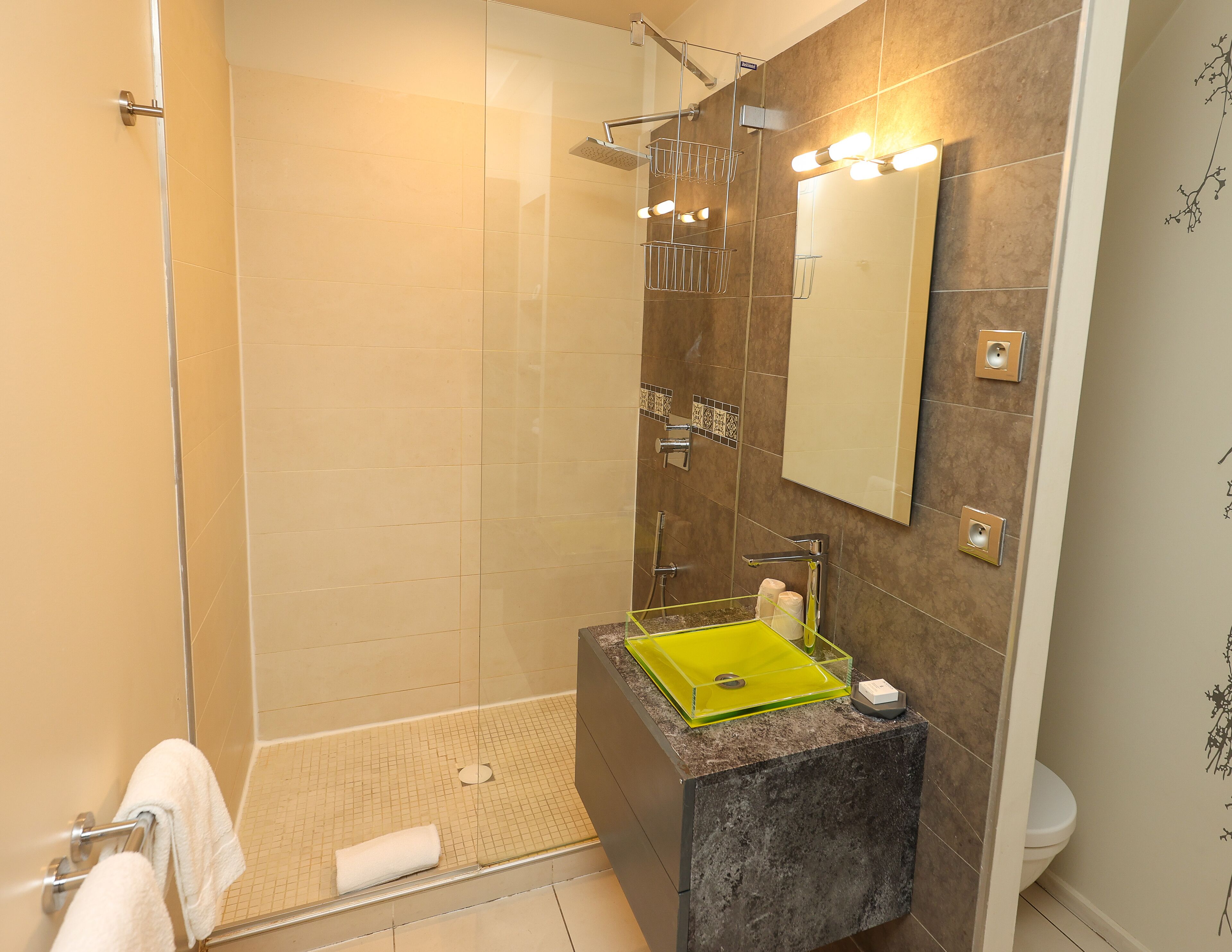 A modern bathroom with a glass-enclosed shower, a vanity with a marble countertop, and a large mirror.