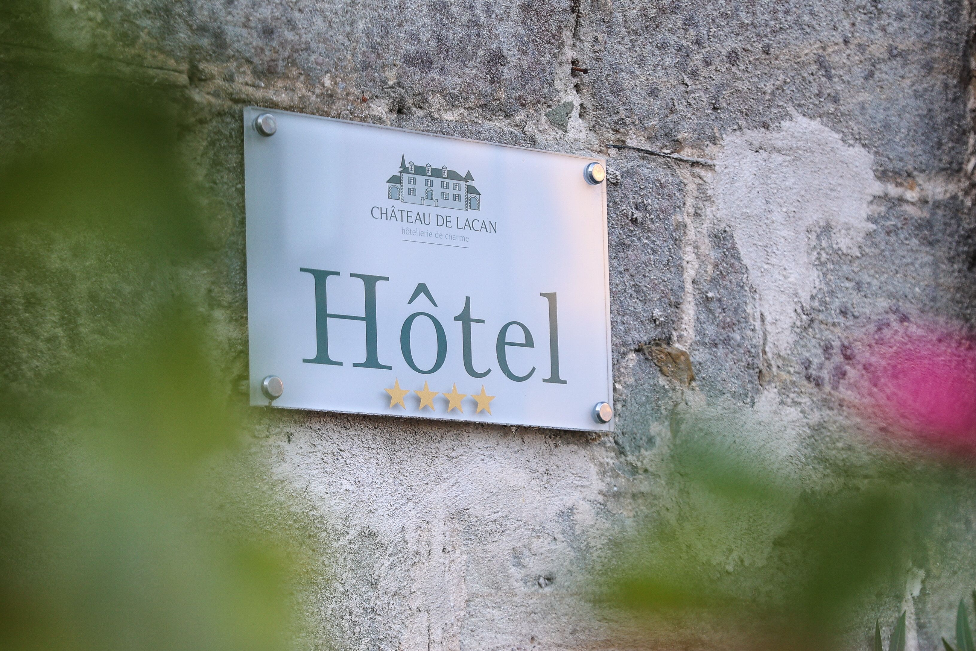 A sign for Château de Lacan hotel with a four-star rating.