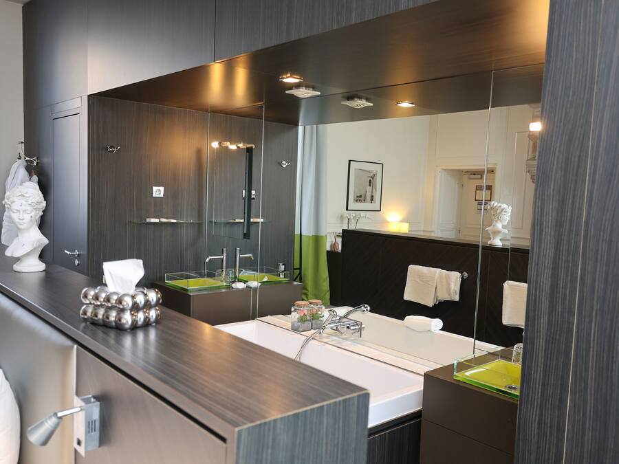 A modern bathroom with a large mirror, two sinks, and a bathtub.