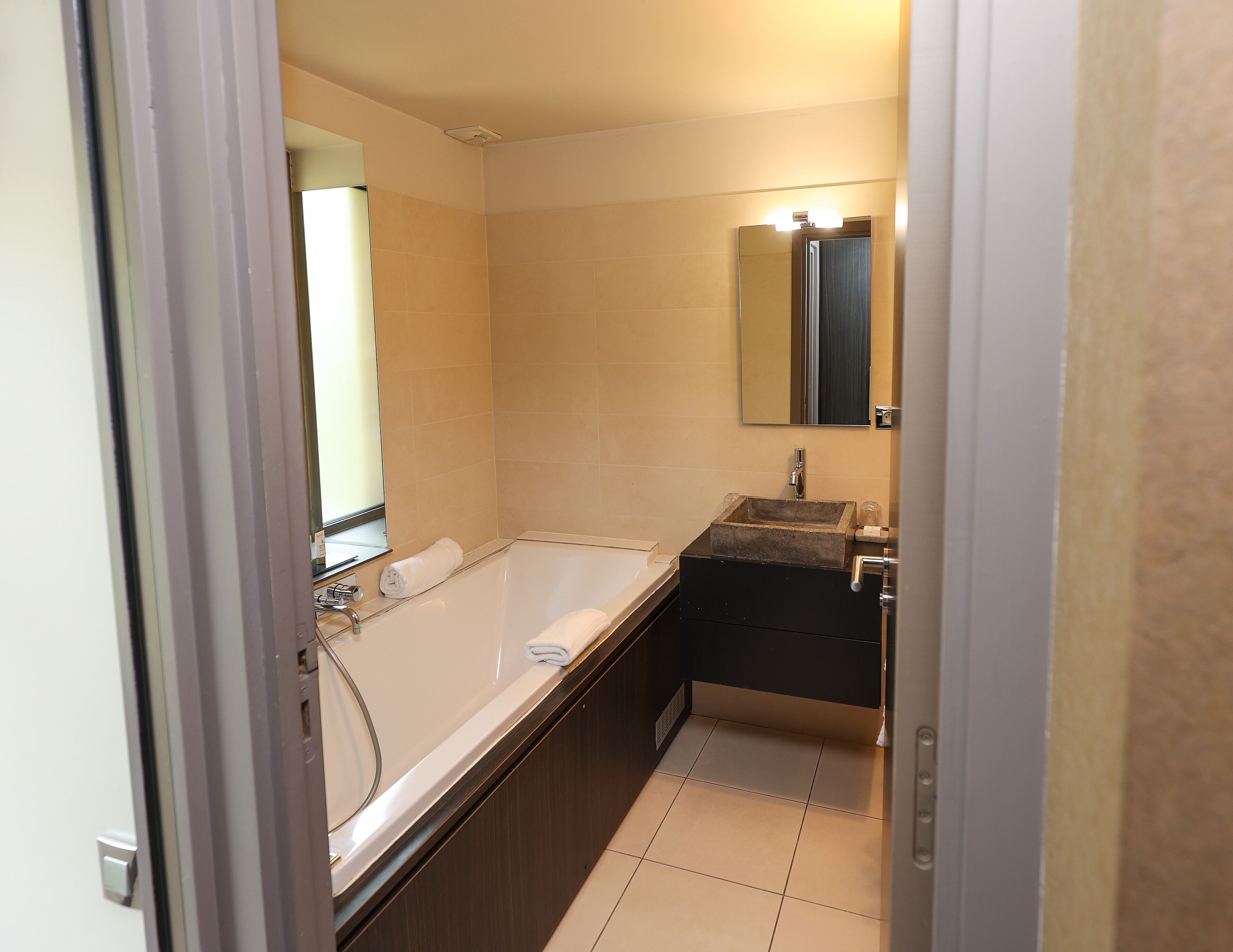 Un baño moderno con bañera, lavamanos y espejo.