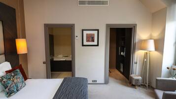 Een hotelkamer met een bed, een bureau, een stoel, een lamp en een schilderij aan de muur.
