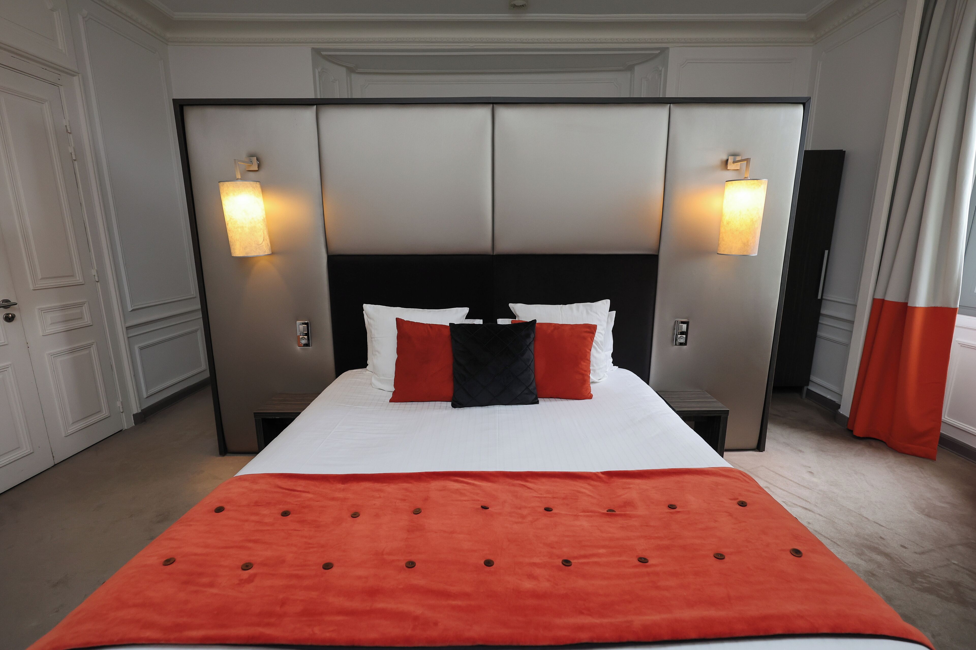 Ein Hotelzimmer mit einem großen Bett, zwei Nachttischen und einem Kopfteil mit integrierter Beleuchtung.