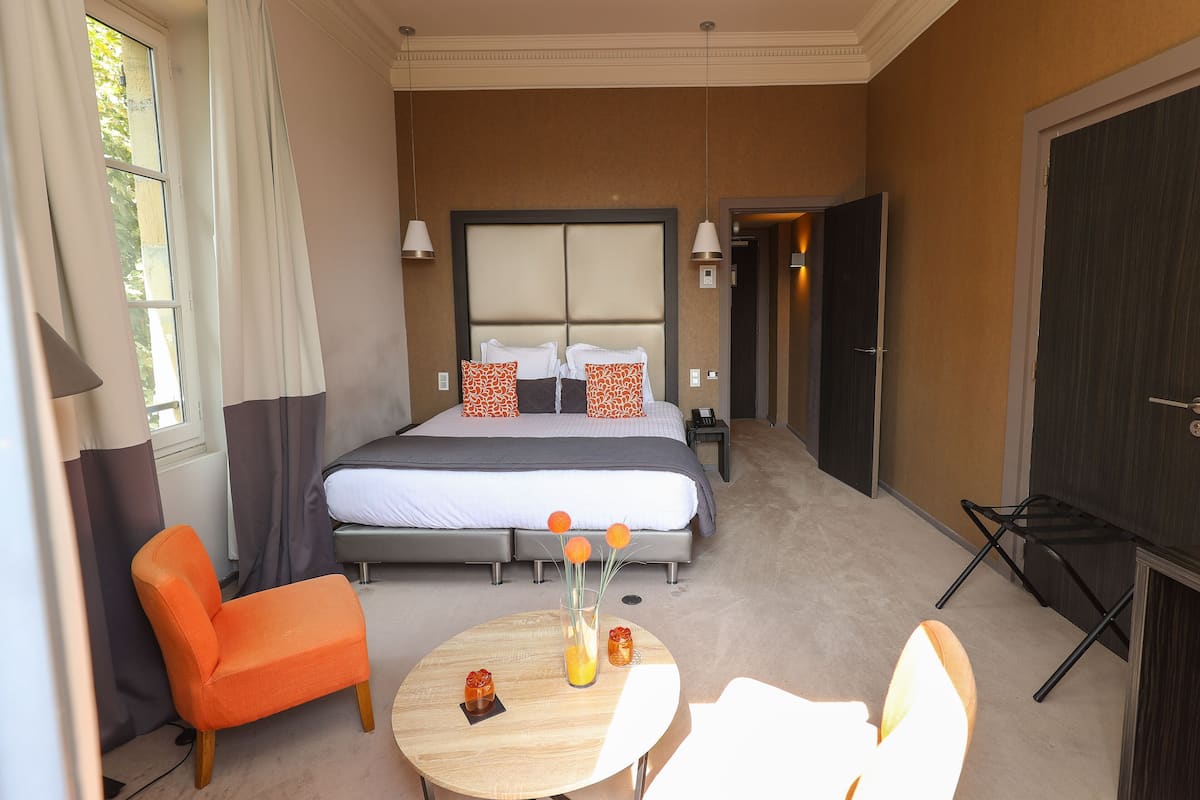 A hotel room with a bed, a chair, a table, and a TV.