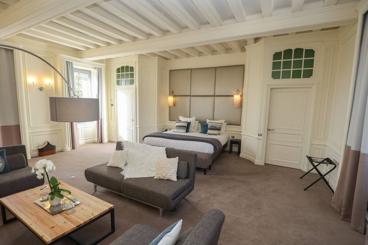 A spacious room with a large bed, a sofa, a coffee table, and a TV.