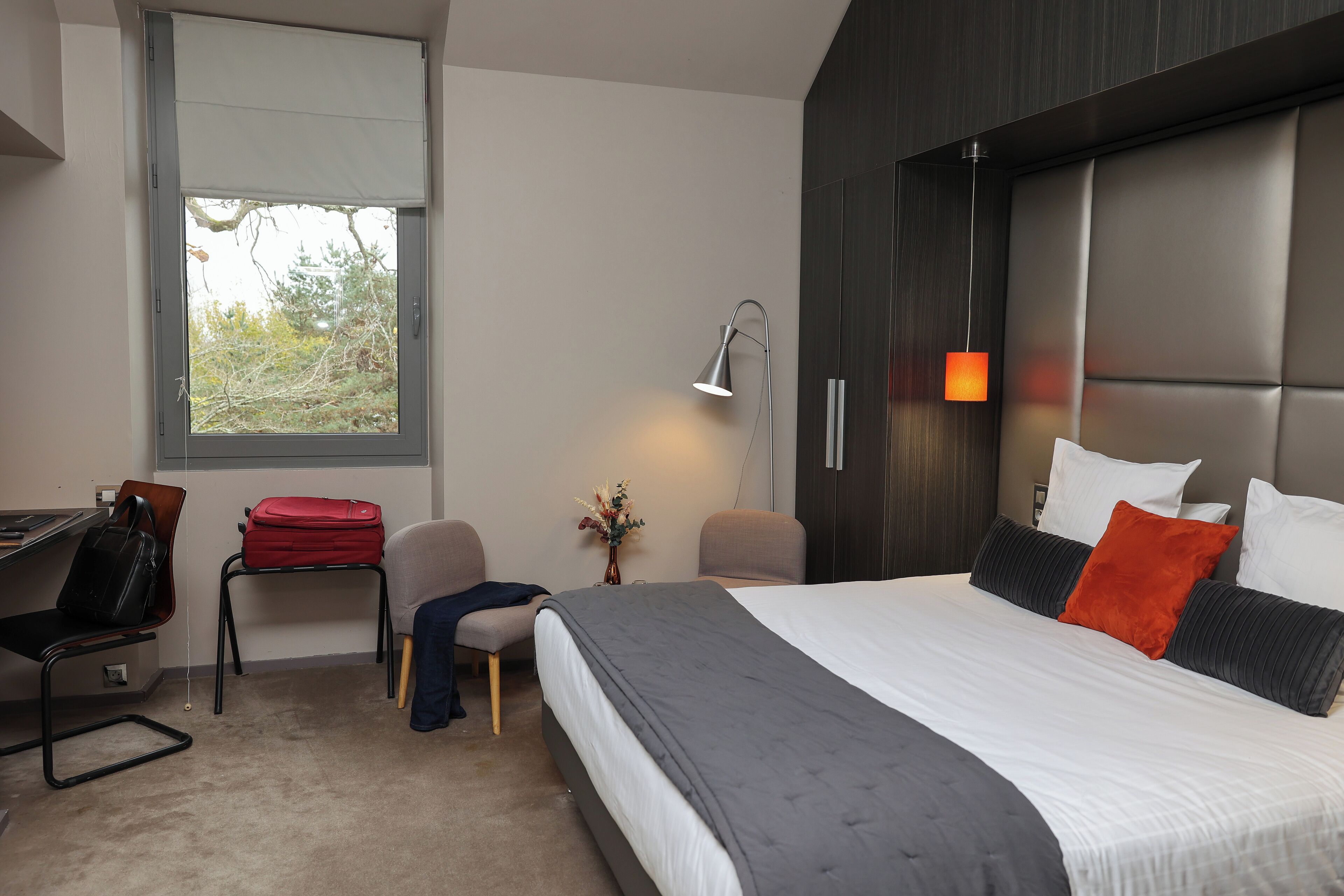 Ett modernt hotellrum med en stor säng, ett skrivbord och en stol.