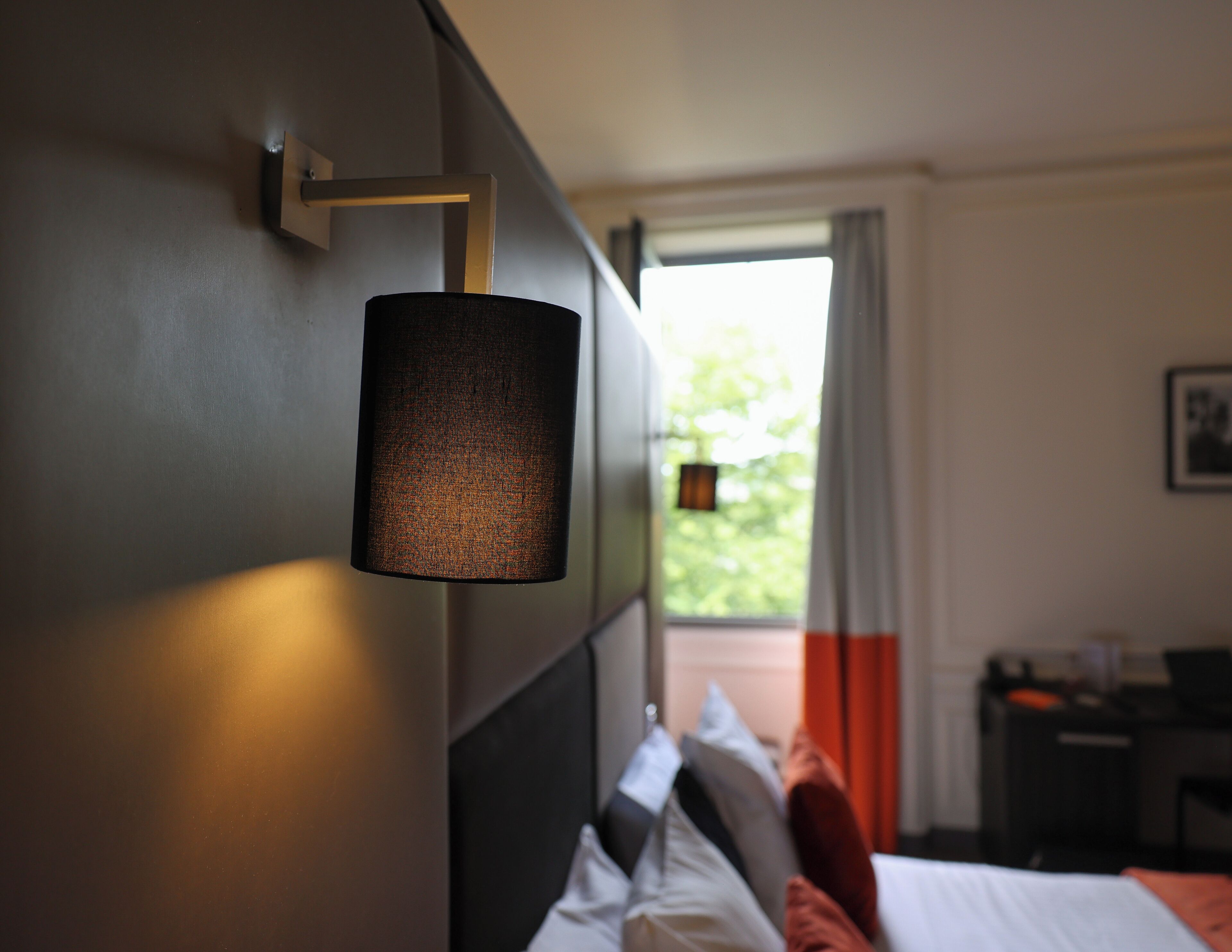 A modern hotel room with a bed, a nightstand, and a lamp.