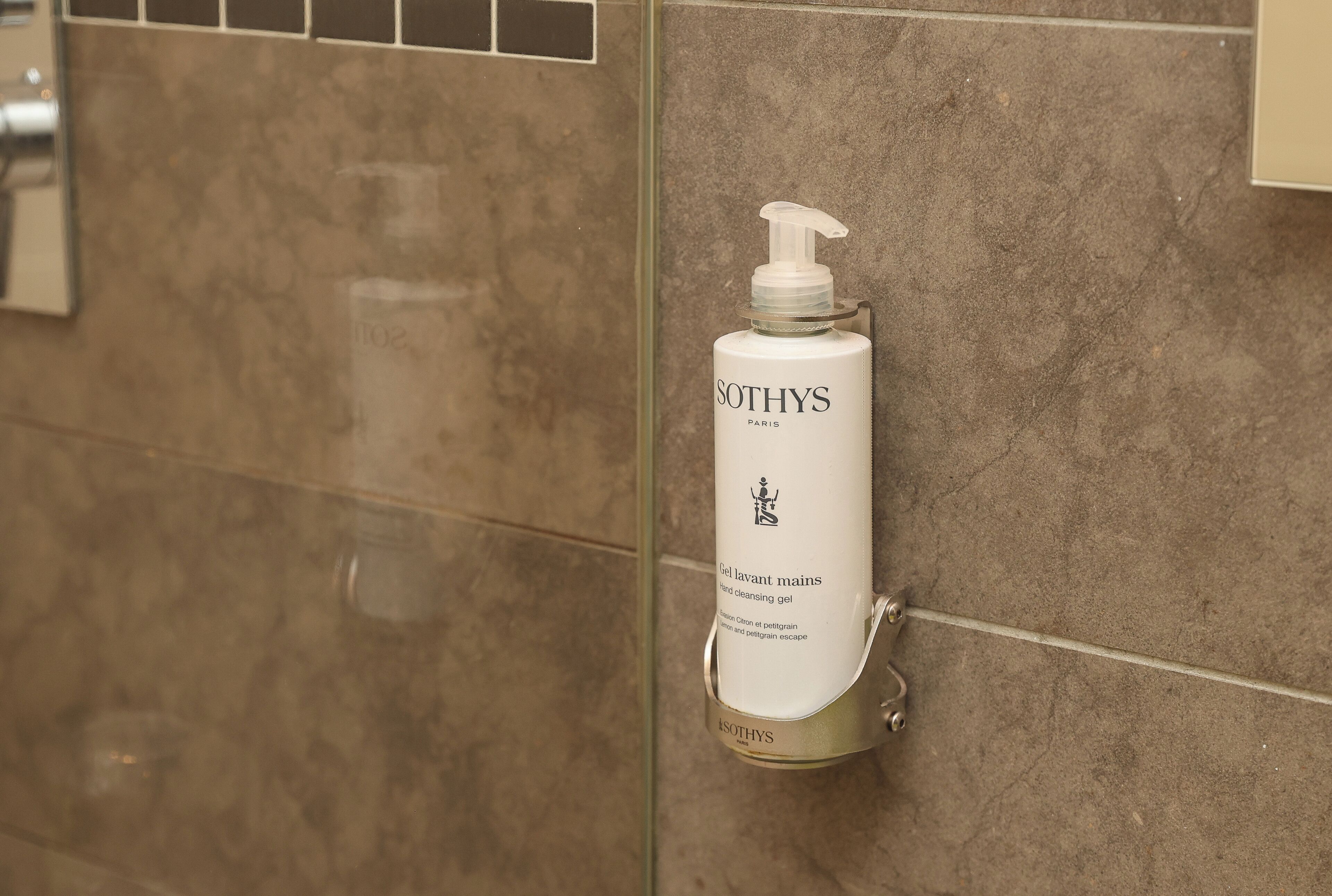 A bathroom with a hand cleansing gel bottle mounted on a wall.