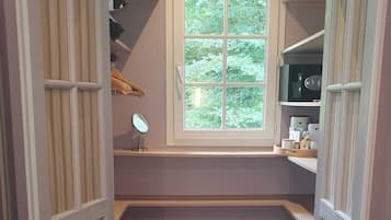A small bathroom with a window, a mirror, shelves, and a tiled floor.