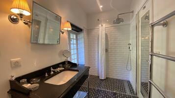 A modern bathroom with a black marble sink, a glass shower enclosure, and a white tiled shower area.