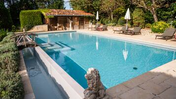A rectangular swimming pool with a stone lion statue in the foreground.