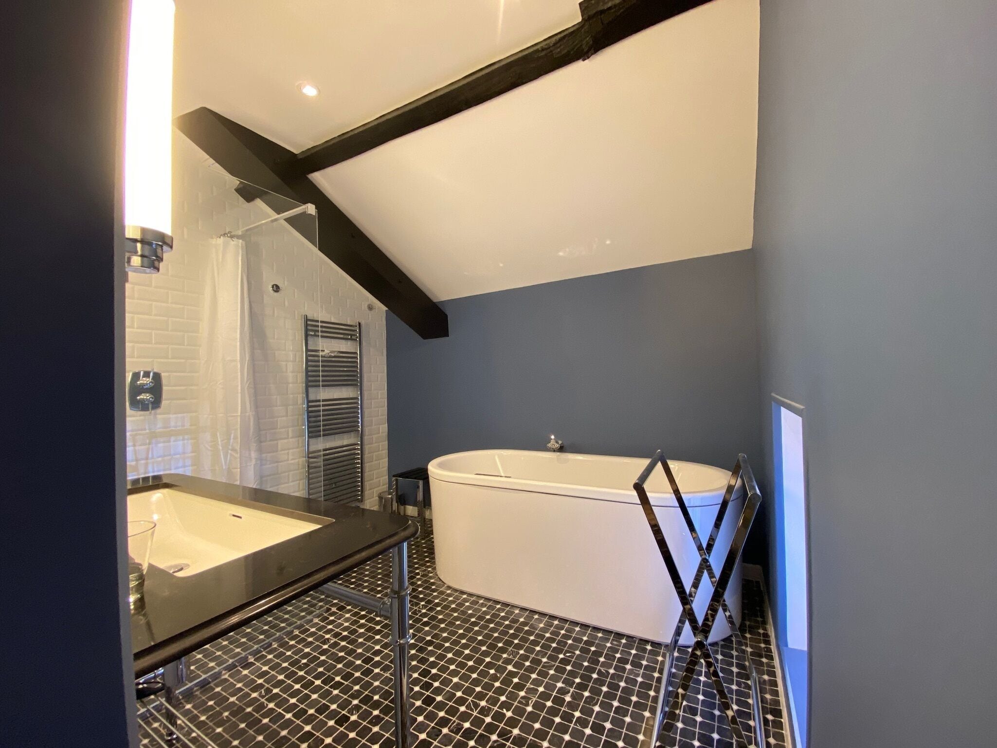 A modern bathroom with a freestanding bathtub, a separate sink area, and a tiled floor.
