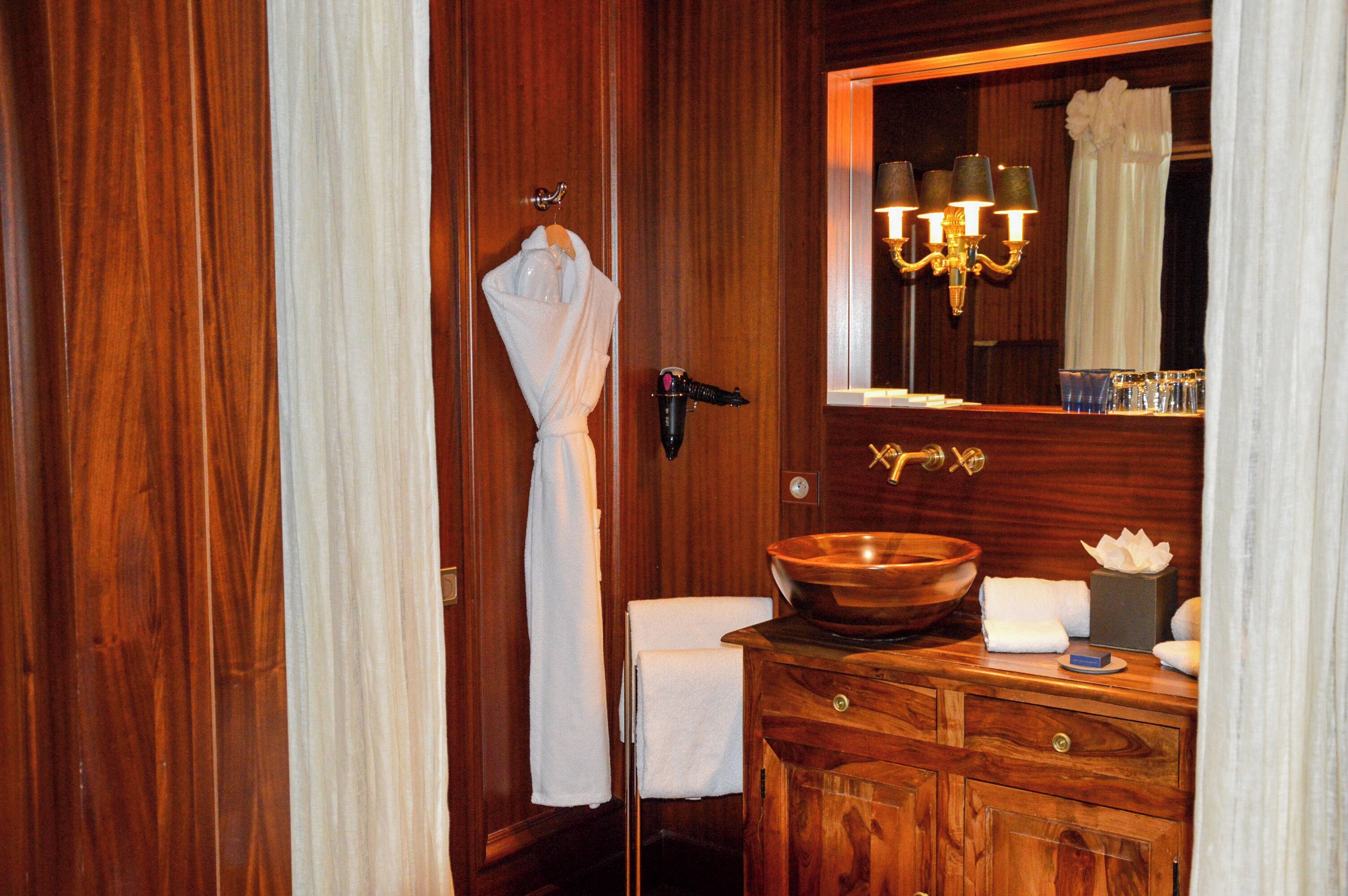 Un baño de madera con un espejo grande, un lavabo de madera y un perchero para toallas.