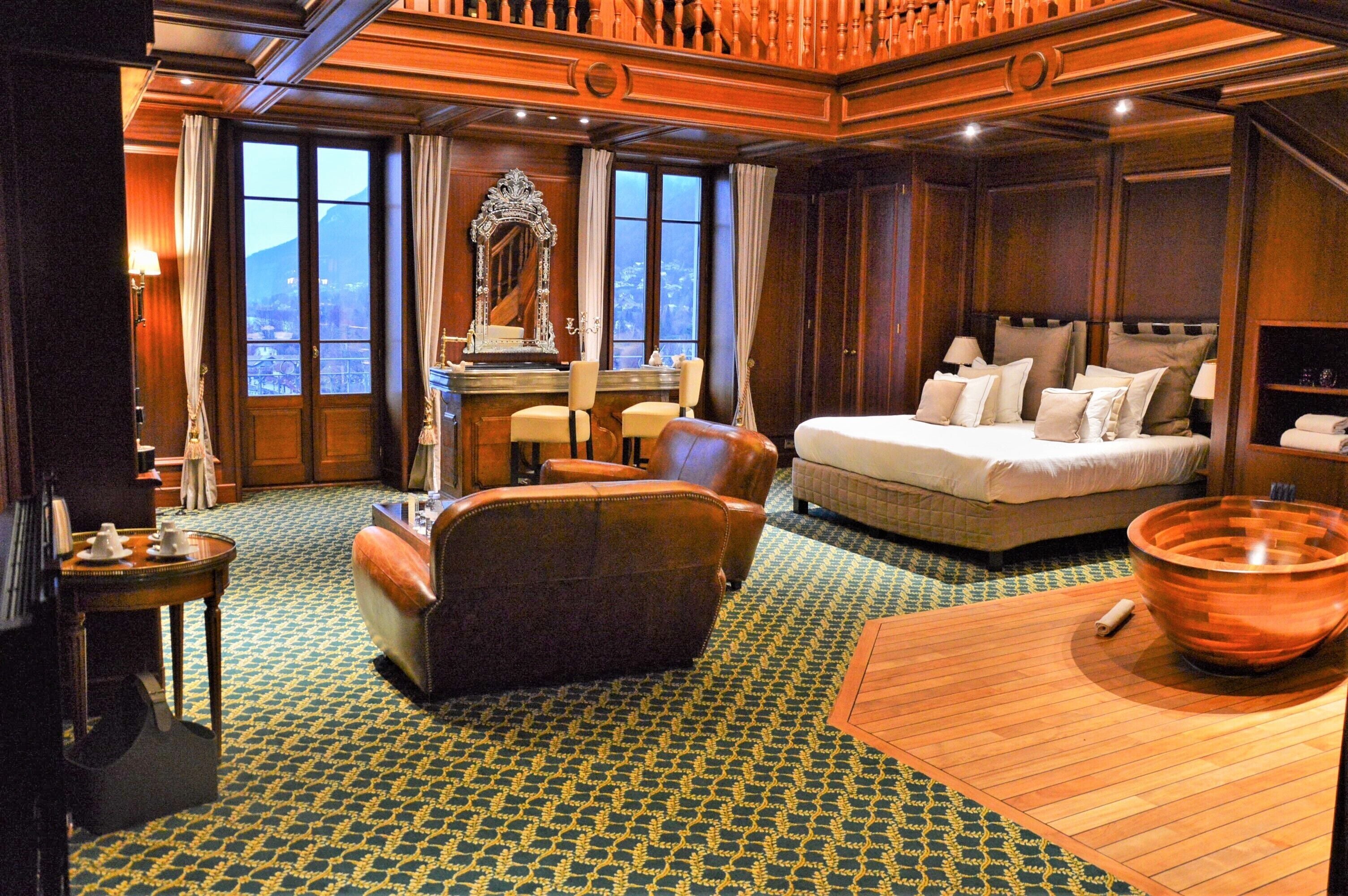Una habitación con cama, zona de estar, espejo grande y vistas a la montaña.