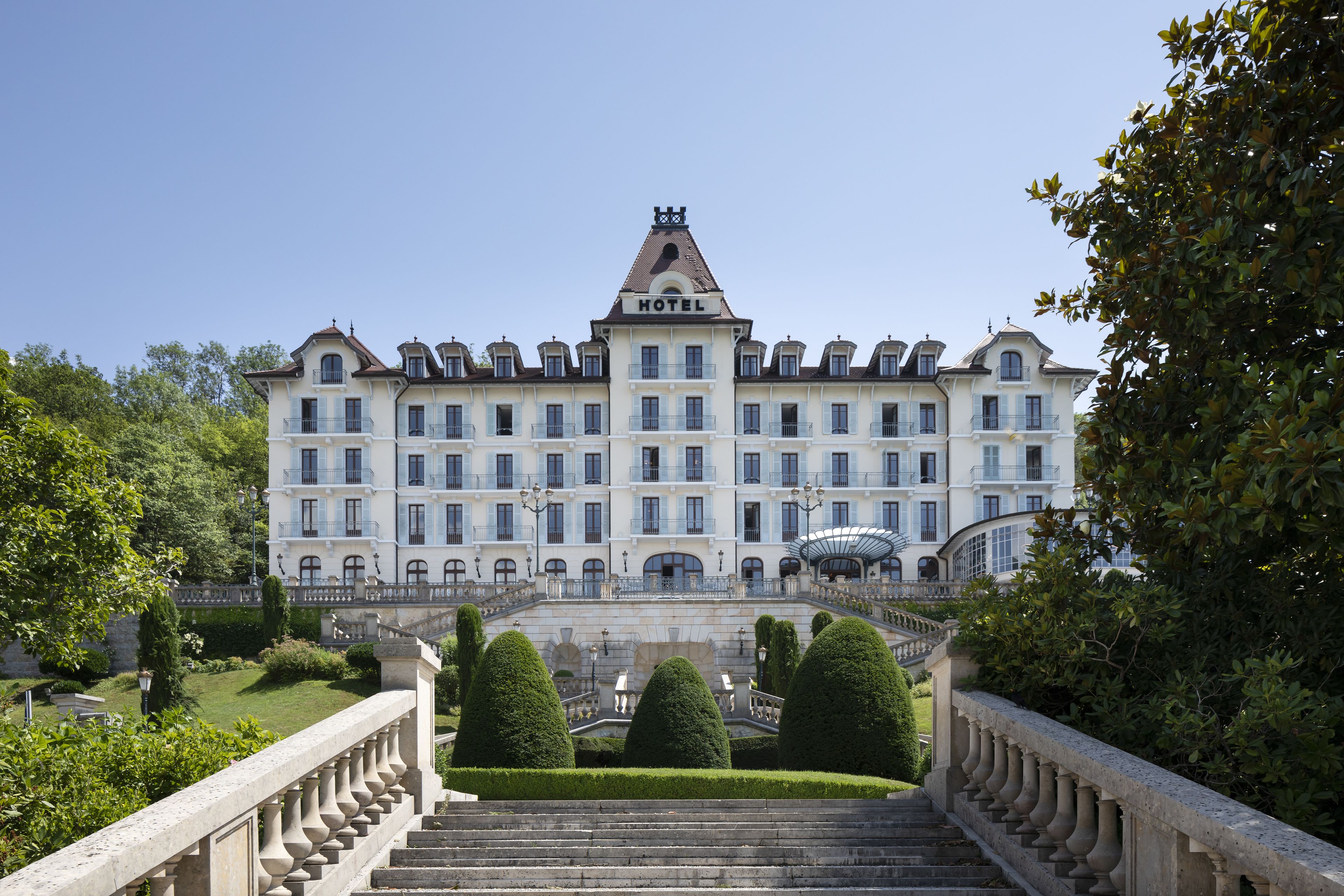 A grand hotel with a symmetrical facade, multiple balconies, and a central entrance with steps leading up to it.
