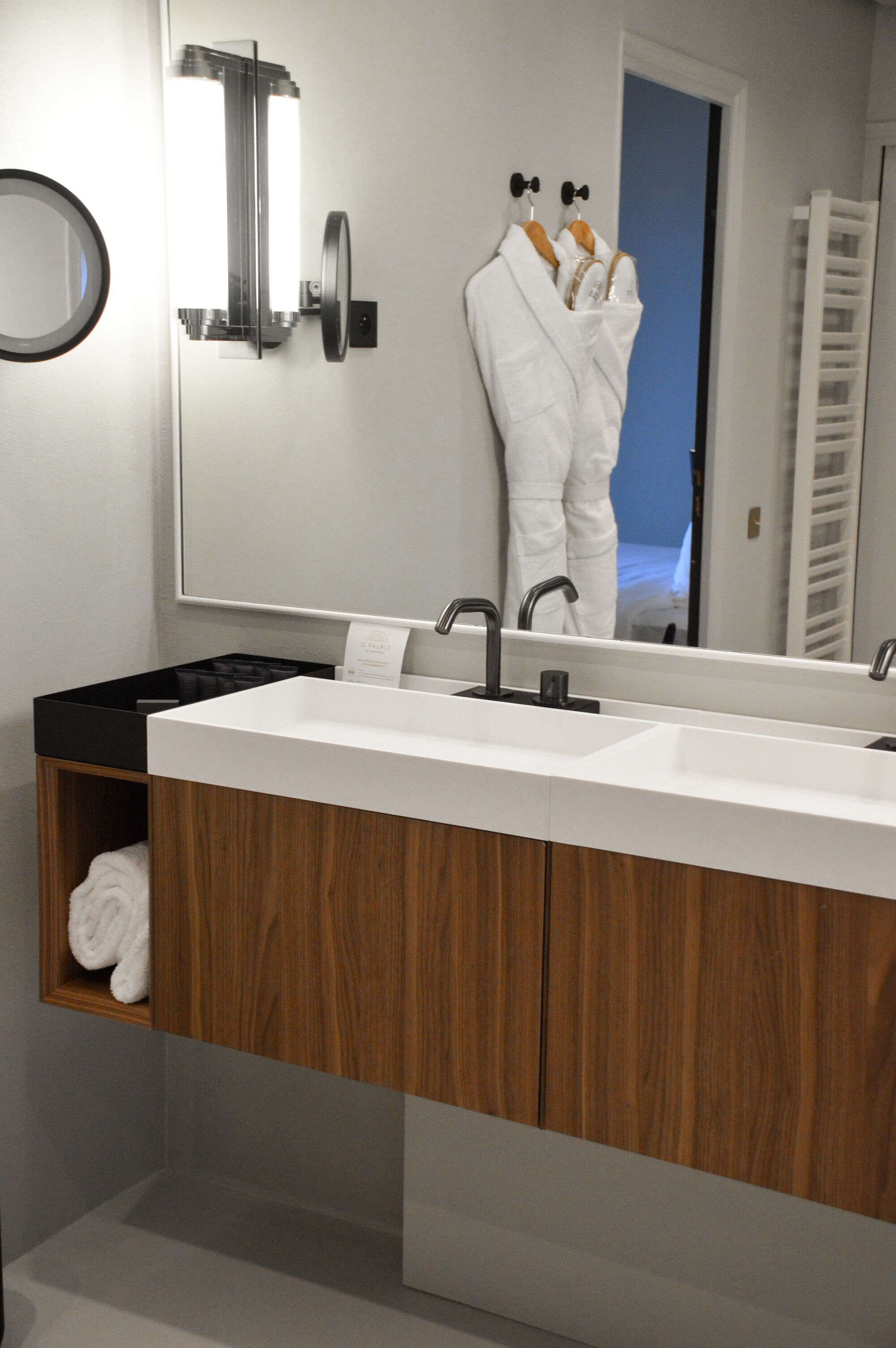 Ein modernes Badezimmer mit großem Spiegel, zwei Waschbecken und Holzschränken.