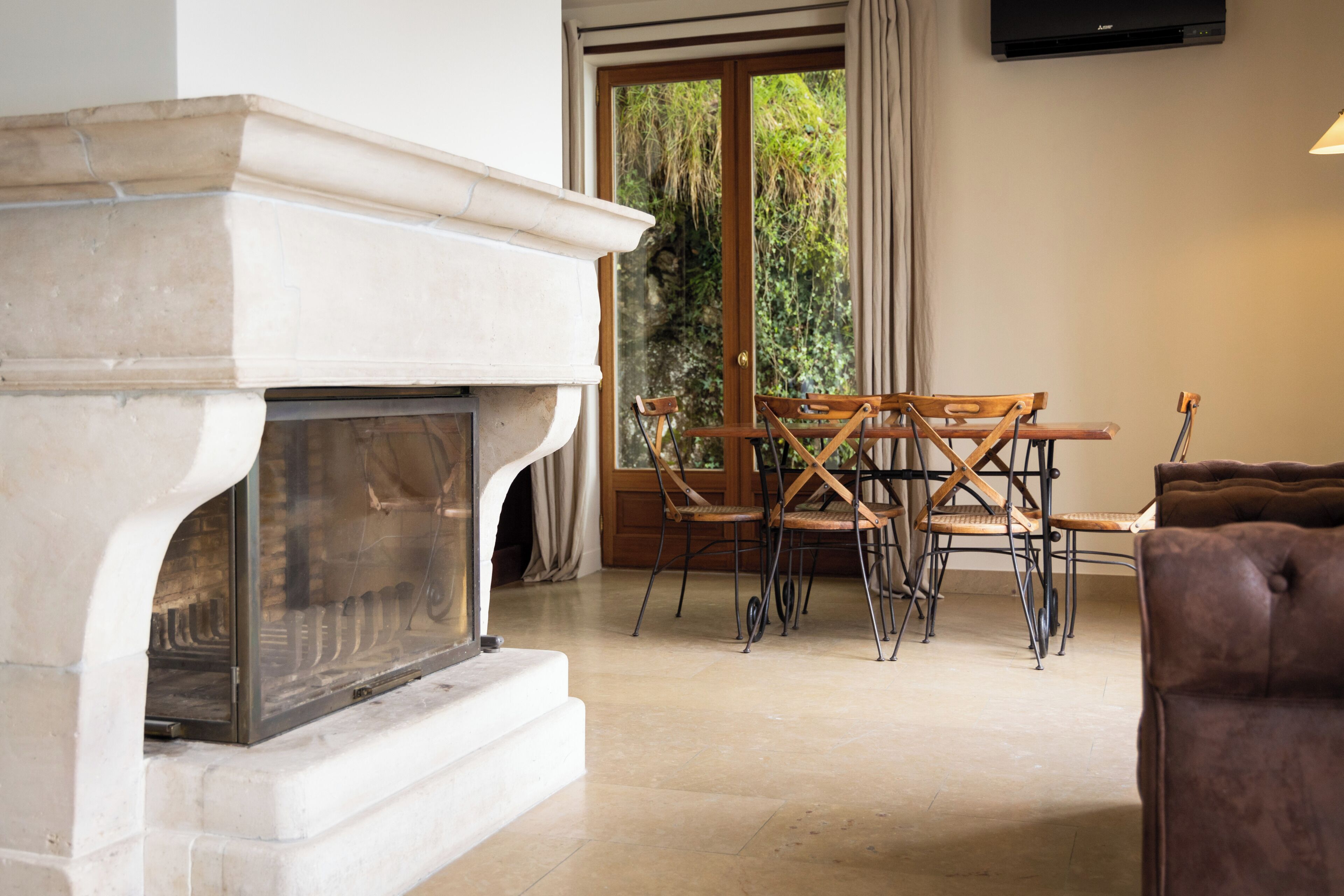 A room with a fireplace, a dining table with chairs, a sofa, and a TV mounted on the wall.